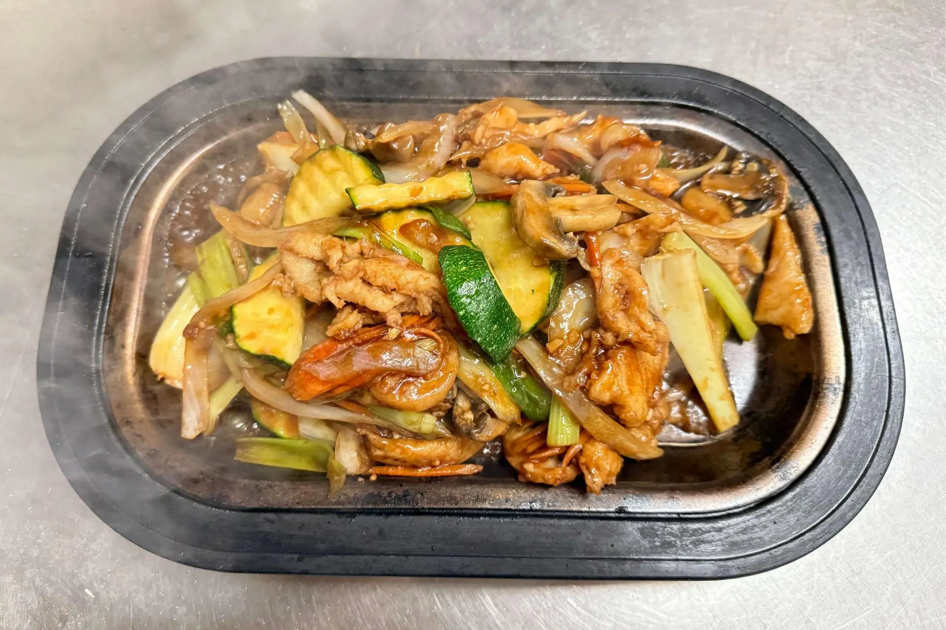 Hot mixed vegetable and chicken stir - fry in a black tray at Ocean Sky, a Chinese Restaurant in Chehalis
